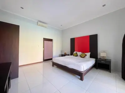 a bedroom with a bed and a red wall at The Lavana Bali Radiance Arjuna Villa Seminyak in Seminyak