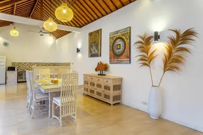a dining room with a table and a vase with a plant at villa mangga 2 chambres seminiak in Seminyak