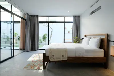 a bedroom with a large bed and large windows at Manresa Villa Bali 1 in Canggu