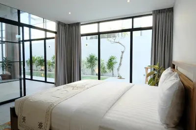 a bedroom with a large bed and large windows at Manresa Villa Bali 1 in Canggu
