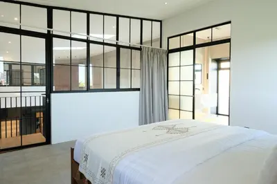 a bedroom with a large bed and large windows at Manresa Villa Bali 1 in Canggu