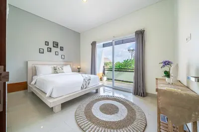 a bedroom with a bed and a large window at De Gani in Seminyak