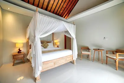 a bedroom with a canopy bed and a table and chairs at Villa Laksmi Legian in Seminyak