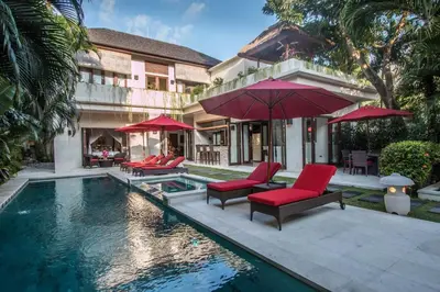 a house with a swimming pool with chairs and umbrellas at Beautiful & Luxurious 3-Bedroom Private Villa With Pool 150-Metres To Seminyak Beach in Seminyak