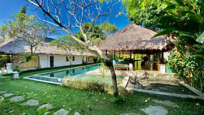 a villa with a swimming pool and a house at Blind Dog Inn in Sanur