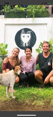 a group of people and a dog in front of a wall at Blind Dog Inn in Sanur