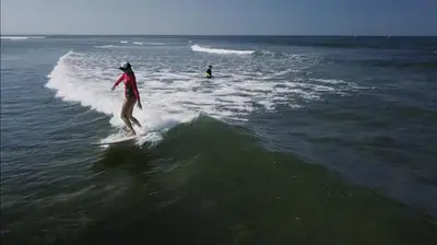 a woman riding a wave on a surfboard in the ocean at Blind Dog Inn in Sanur