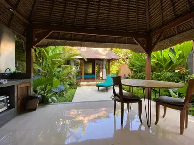 a dining room with a table and chairs and a patio at Little Tree House in Sanur