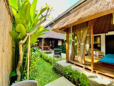 a resort with a palm tree next to a building at Little Tree House in Sanur