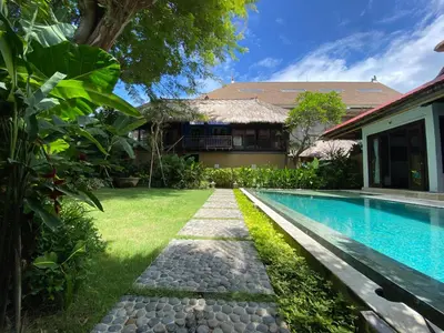 a backyard with a swimming pool and a house at Little Tree House in Sanur