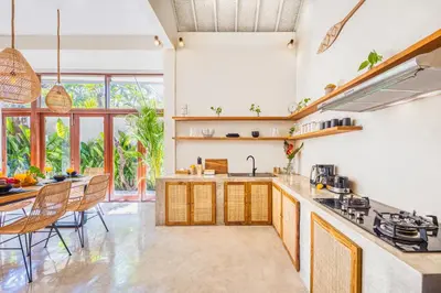 a kitchen with wooden cabinets and a table with chairs at NEW Fresh 3BD Prime Location Villa in Seminyak