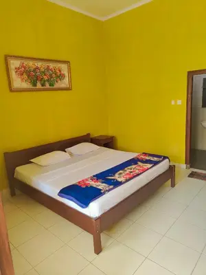 a bed in a room with a yellow wall at Berlian Inn Kuta Beach in Kuta