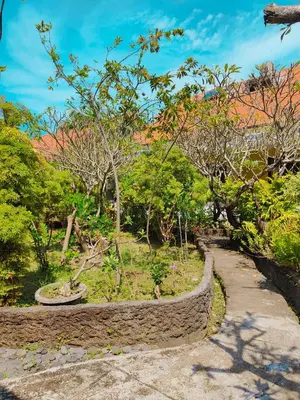 a stone path in a park with trees and bushes at Berlian Inn Kuta Beach in Kuta