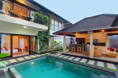 a villa with a swimming pool in front of a house at Agata Villas Seminyak in Seminyak