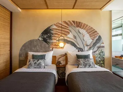two beds in a room with a mural on the wall at The Isvara by Cove in Seminyak