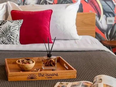 a wooden tray with a bowl of food on a bed at The Isvara by Cove in Seminyak