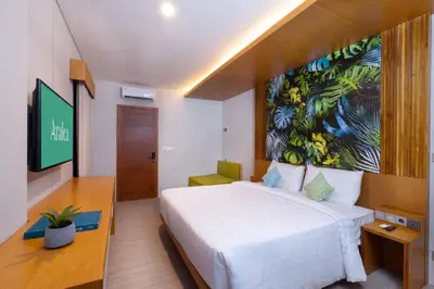 a bedroom with a white bed and a large painting on the wall at Aralea Coliving in Denpasar