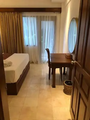 a bedroom with a bed and a desk and a table at The Palmana Courtyard Jayakarta Residence 2 in Seminyak