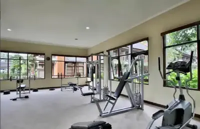 a gym with treadmills and ellipticals and windows at The Palmana Courtyard Jayakarta Residence 2 in Seminyak