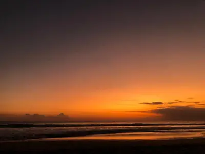 a sunset on a beach with the ocean at The Palmana Courtyard Jayakarta Residence 2 in Seminyak