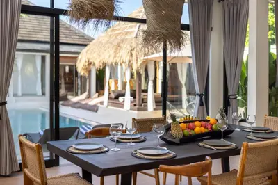 a dining table with a bowl of fruit and wine glasses at Villa Matahari - Seminyak in Seminyak