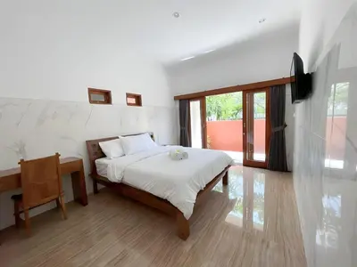 a bedroom with a bed and a table and a window at Kubu19 Guest House in Seminyak