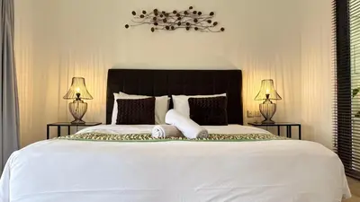 a bedroom with a large white bed with two lamps at Solaris Private Villa Club Residence Canggu in Canggu