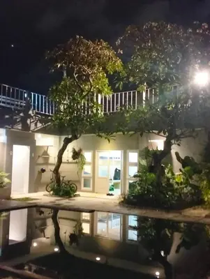 a house at night with a tree in the foreground at The Island Bali in Seminyak