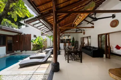 an outdoor living room with a pool and a villa at Villa Belharra in Seminyak