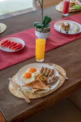 a table with a plate of breakfast food on it at New Villa Selamanya in Ujung