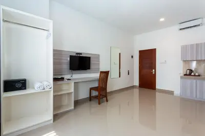 a white room with a desk with a television and a chair at Cove De Tinaya in Legian