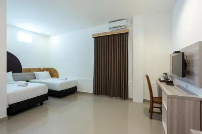 a hotel room with two beds and a tv at Cove De Tinaya in Legian