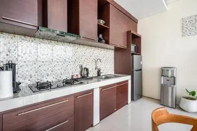 a kitchen with wooden cabinets and a sink and refrigerator at The R Villa Toba - incl. Motorbikes in Seminyak