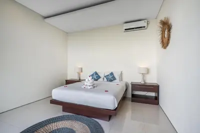 a white bedroom with a bed and a night stand at The R Villa Toba - incl. Motorbikes in Seminyak
