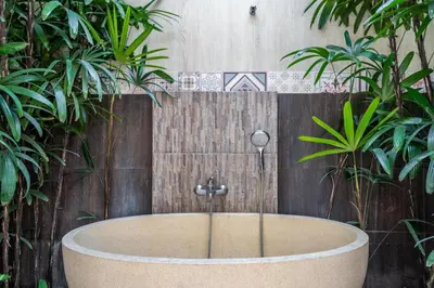 a bath tub in front of a fence with plants at The R Villa Toba - incl. Motorbikes in Seminyak