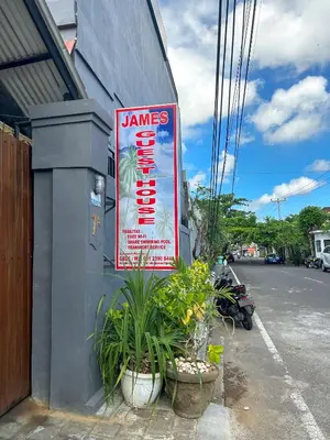 a sign on the side of a building with plants at James Guest House in Seminyak