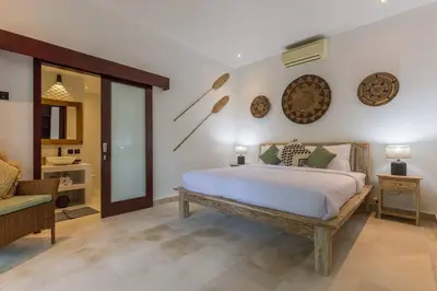 a bedroom with a large bed and a chair at Villa Budha 1: 4bedrs 12m Pool, 700m2 garden with BBQ in Seminyak