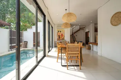 a dining room with a table and a swimming pool at Villa Kainara 2 - Cozy villa in center of Seminyak in Seminyak
