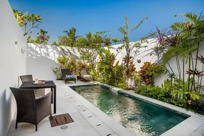 a swimming pool in a garden with a table and chairs at Villa Balik I Seminyak in Seminyak