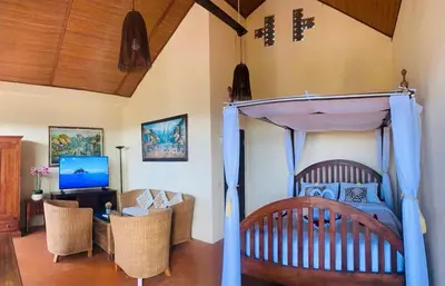 a bedroom with a bed and a living room at Giri's Villa Jimbaran in Jimbaran