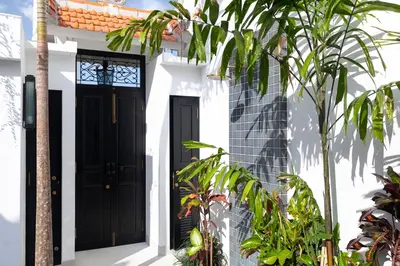a black door on a white house with plants at Martini Beachside Villa 3 in Canggu