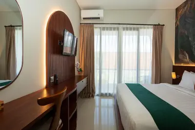 a hotel room with a bed and a desk and a mirror at Cove Ransha Stay in Sanur