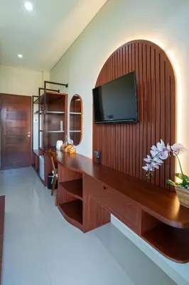 a living room with a tv on a wooden wall at Cove Ransha Stay in Sanur