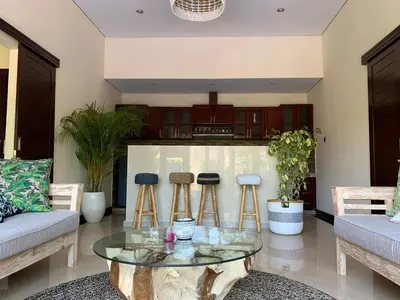 a living room with a glass table and stools at Villa Olga in Seminyak