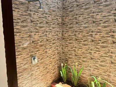 a shower in a bathroom with a stone wall at Villa Olga in Seminyak
