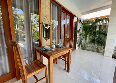 a balcony with a wooden table and a chair at Villa Majegau 2 Seminyak in Seminyak