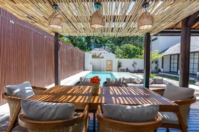 an outdoor patio with a wooden table and chairs at Green Jimbaran Bay Villa in Jimbaran