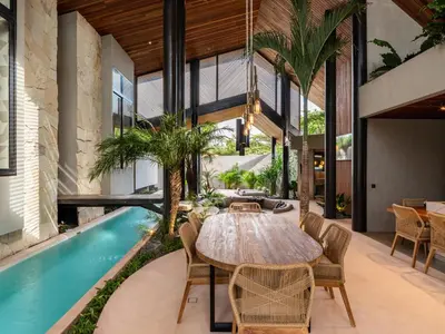an indoor dining room with a table and a swimming pool at Villa FEH Bali by House of Winds - Neo Tropical Eden near Canggu in Kerobokan