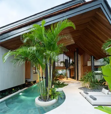 an indoor pool with palm trees in front of a house at Villa Levante Bali by House of Winds - Tropical Oasis near Canggu in Kerobokan