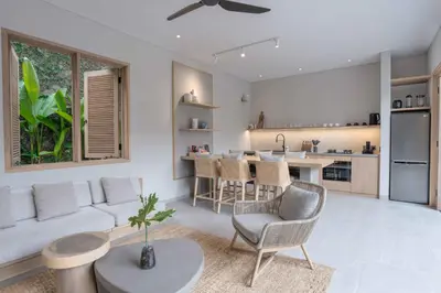 a living room with a couch and a kitchen at Sin Nombre Bali - Sauna, Ice Bath & Roof Terrace in Canggu